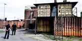 <span style='font-family: Arial; font-size: 15px; color: White;'>Alle på nær en kom ud. Man fandt man manden, hvis hænder holdt krampeagtigt fast i et gelænder inde i bygningen bag den gule containerbygning. </span> <span style='font-family: Arial; font-weight: normal; font-size: 15px; color: #999999;'>Foto: Klaus Lange</span>