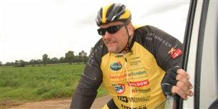 Amin Jensen får sig her et velfortjent hvil ved at hægte sig på følgebilen. Normalt sidder han ikke på en cykelsaddel, men underholder det ældre segment med sang og gakkede gøglerier.