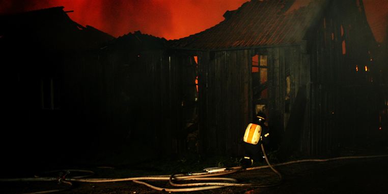 Billedet er taget, da fem kanonbådsskure stod i brand på Holmen i Københavns den 18. august 2006. På brandmandens ryg ses apparatet Travox 120. Det blev i et brev til ledelsen beskrevet som ikke egnet til ildebrande af brandmænd 13 dage efter billedet blev taget.