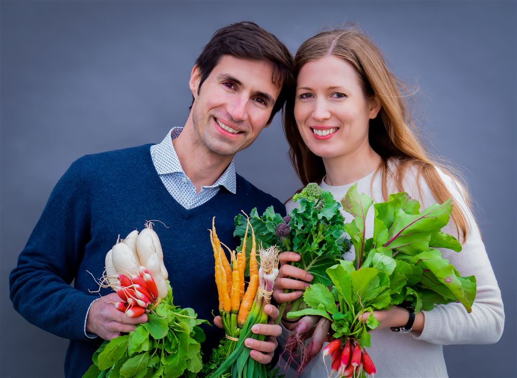 Et smilende par med grøntsager i favnen