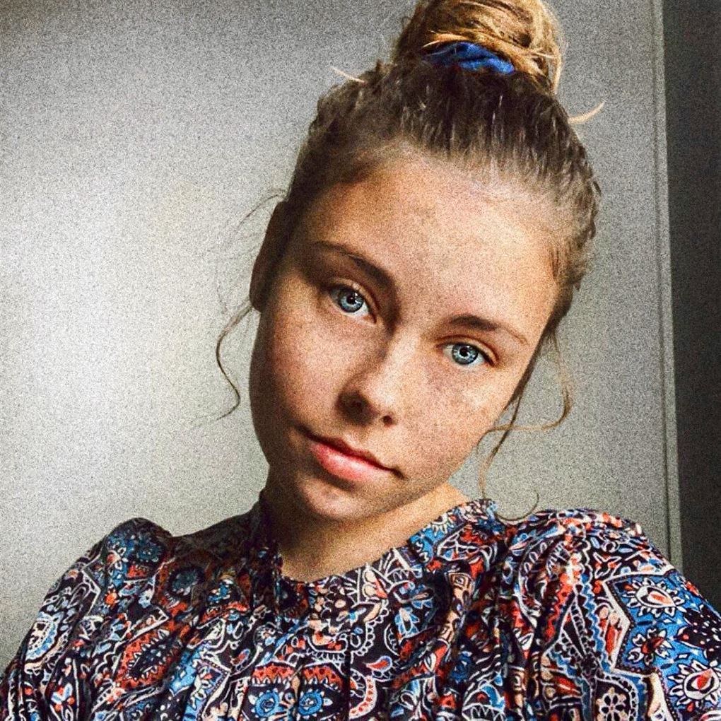 En ung kvinde med opsat hår i en knold og meget blå øjne. 