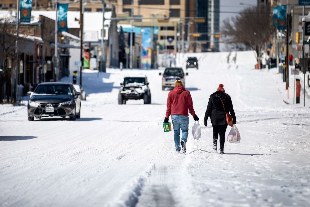 folk går på gade hvor der ligger sne