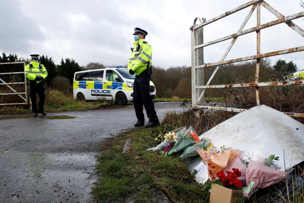Blomster ved indkørsel, politimand holder vagt