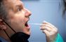 En mand bliver testet med en lang vatpind i munden. 