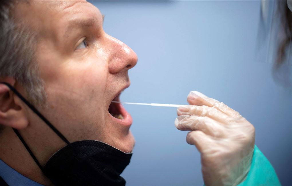 En mand bliver testet med en lang vatpind i munden. 