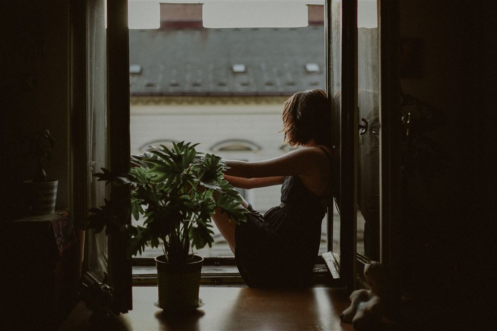 En kvinde sidder i et åbent vindue