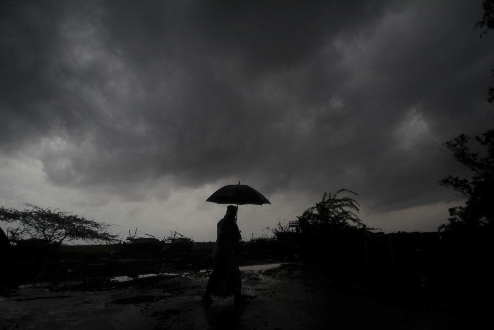 person går med paraply under sorte skyer på himlen 