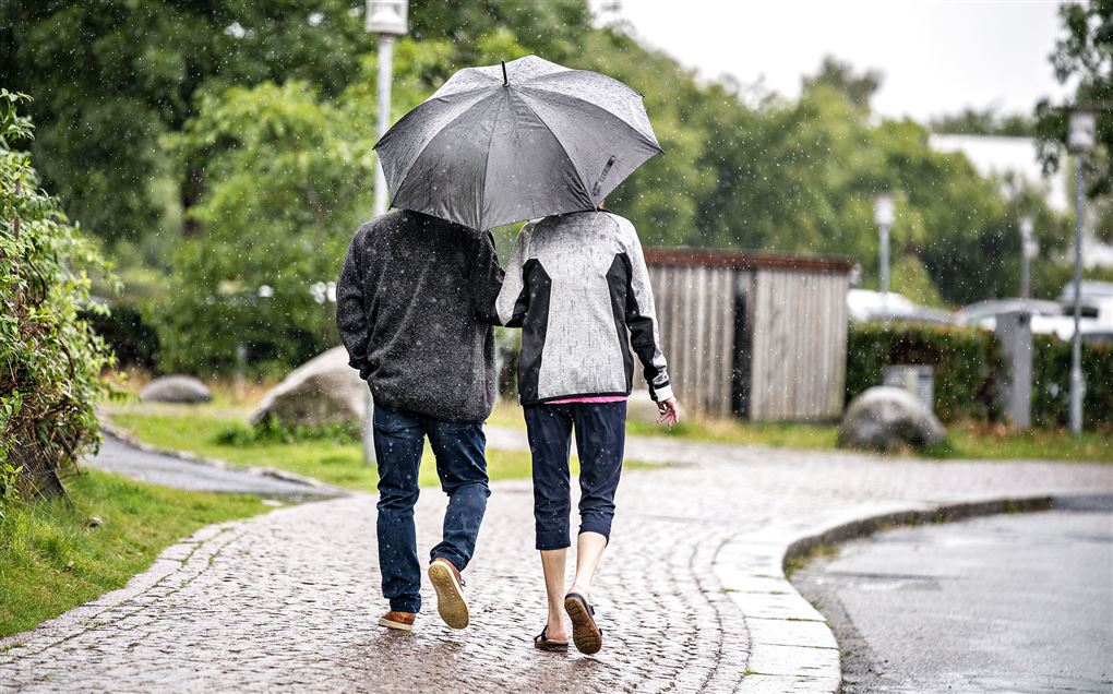 par går på fortov under paraply