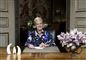 Dronning Margrethe sidder ved bord og smiler 