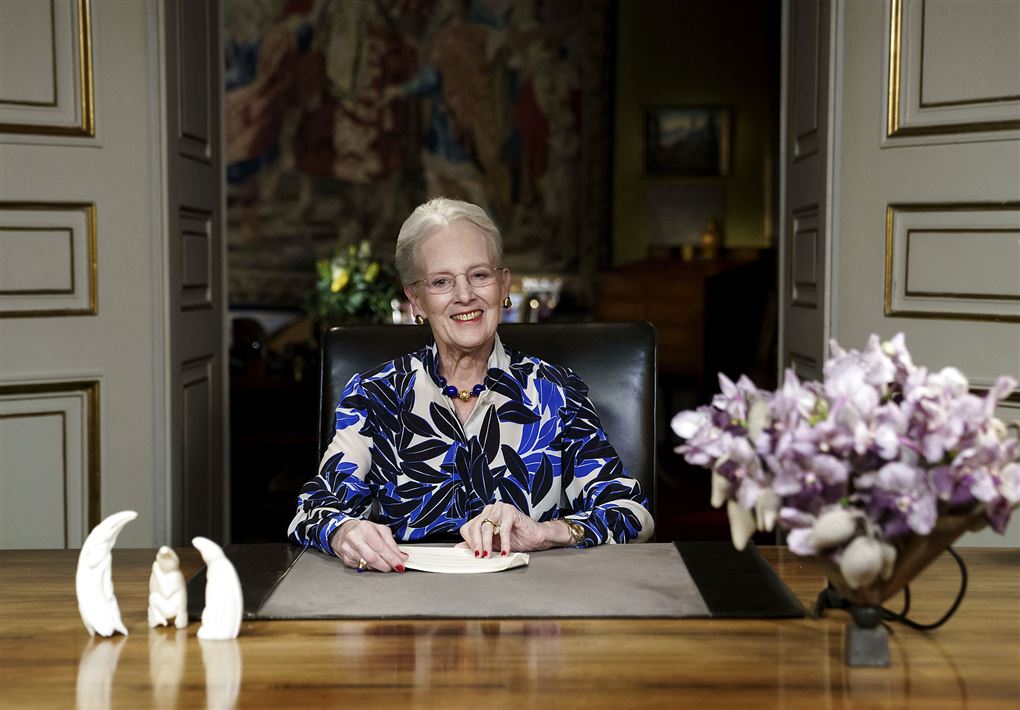 Dronning Margrethe sidder ved bord og smiler 
