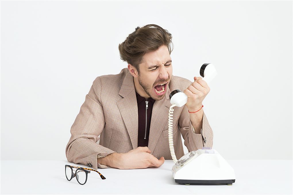En mand råber ind i et telefonrør