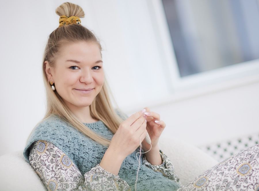kvinde med strikketøj smiler 