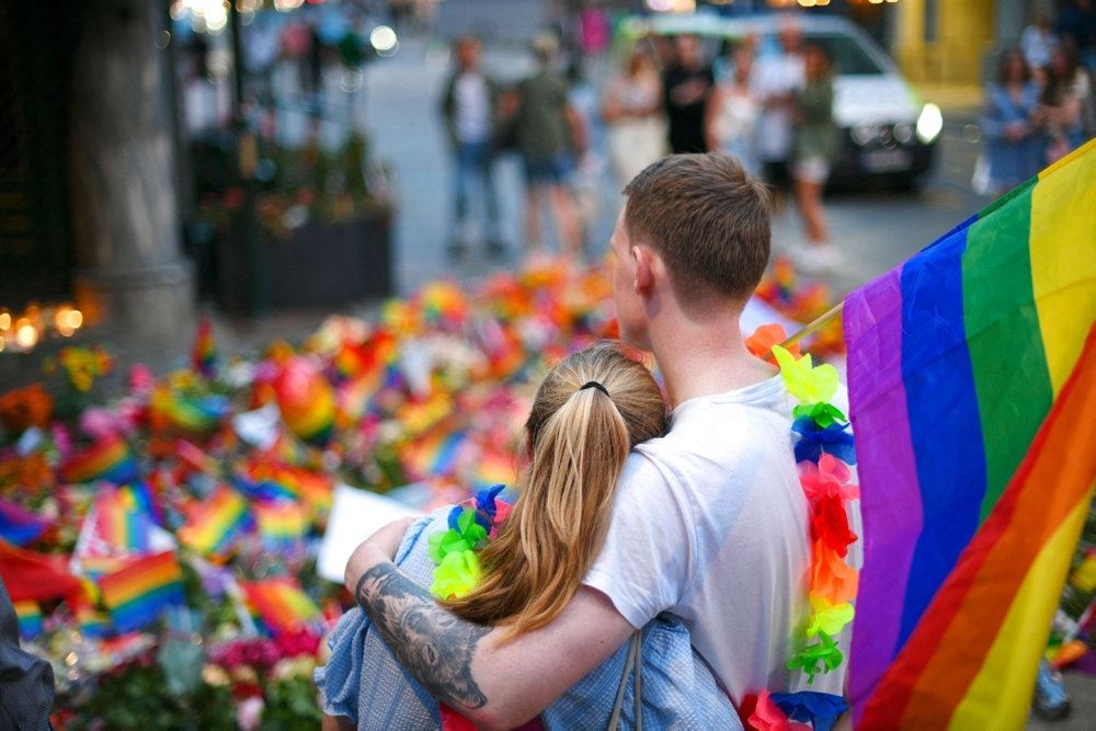 par står og kigger på blomster og regnbueflag