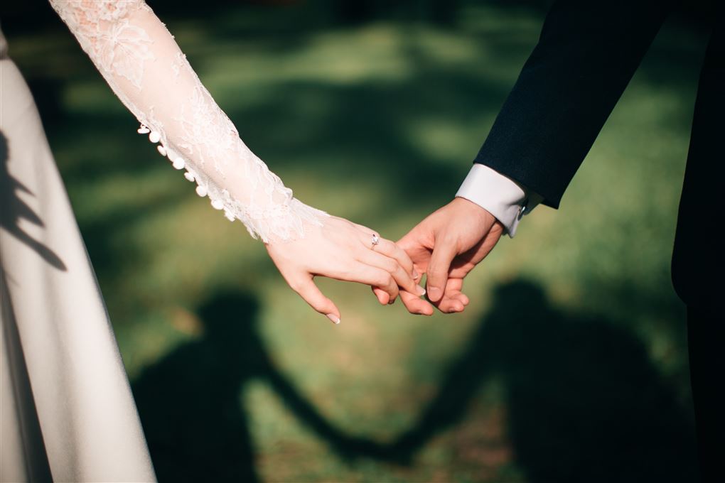 Et brudepar der holder i hånden man kan kun se deres arme.