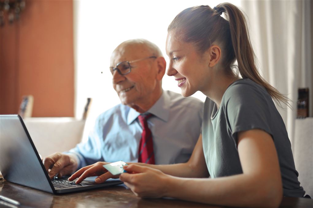 en ældre man og en yngre kvinde ved en laptop