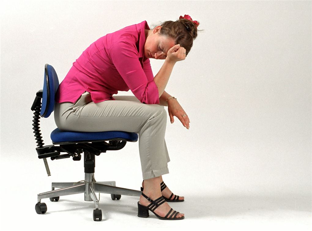 En kvinde med hovedpine sidder på en stol