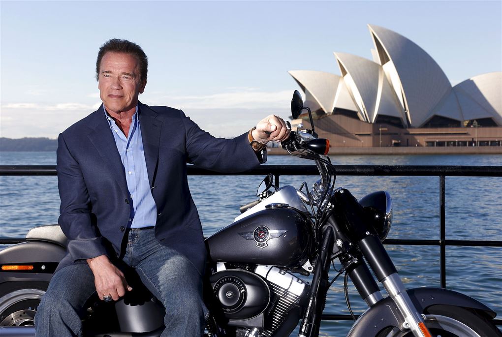 Arnold Schwarzenegger på motorcykel med Sydney Opera Hus i baggrunden.