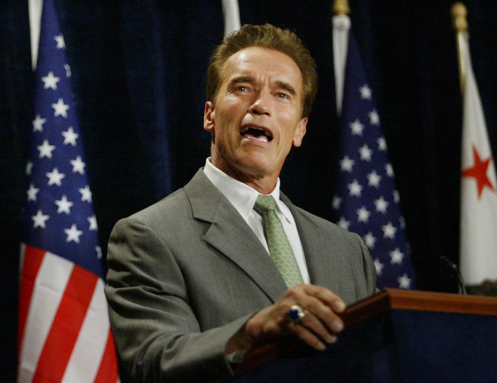 Arnold Schwarzenegger på talerstol med det amerikanske flag bag sig.