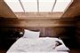 En sovende kvinde i en kæmpe seng med et ovenlysvindue over sig