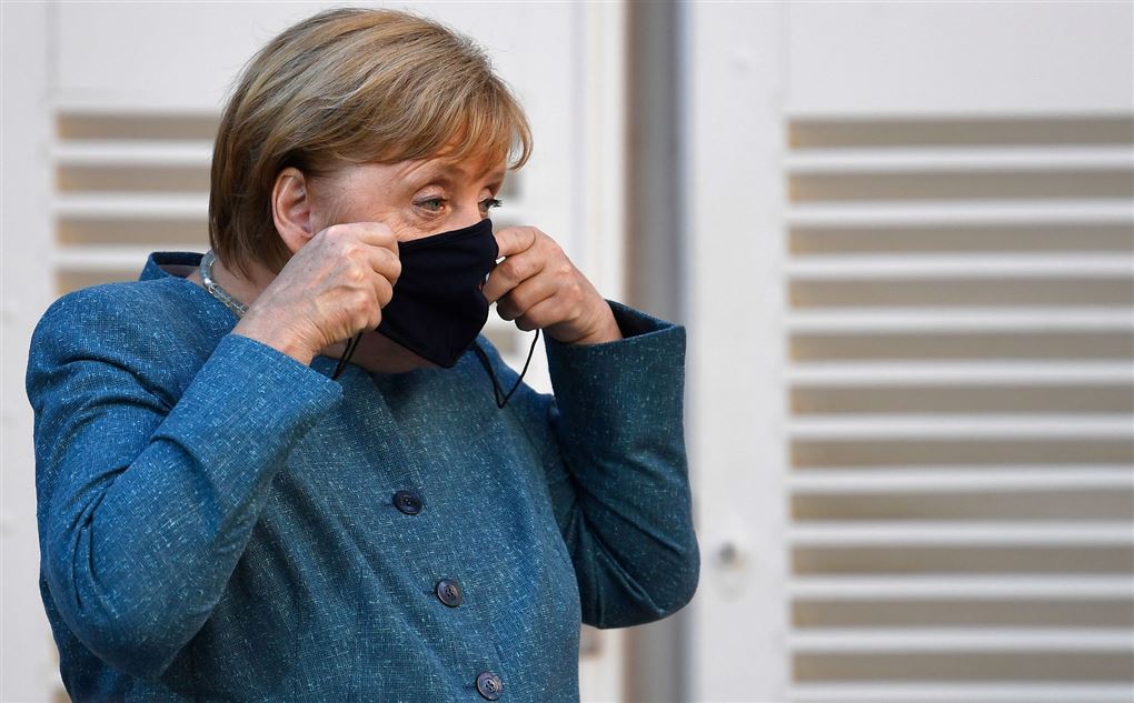 Angela Merkel i blå kjole med et sort mundbind.