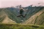 En pige hopper op i luften i træningstøj - forgrunden er et bjergpas