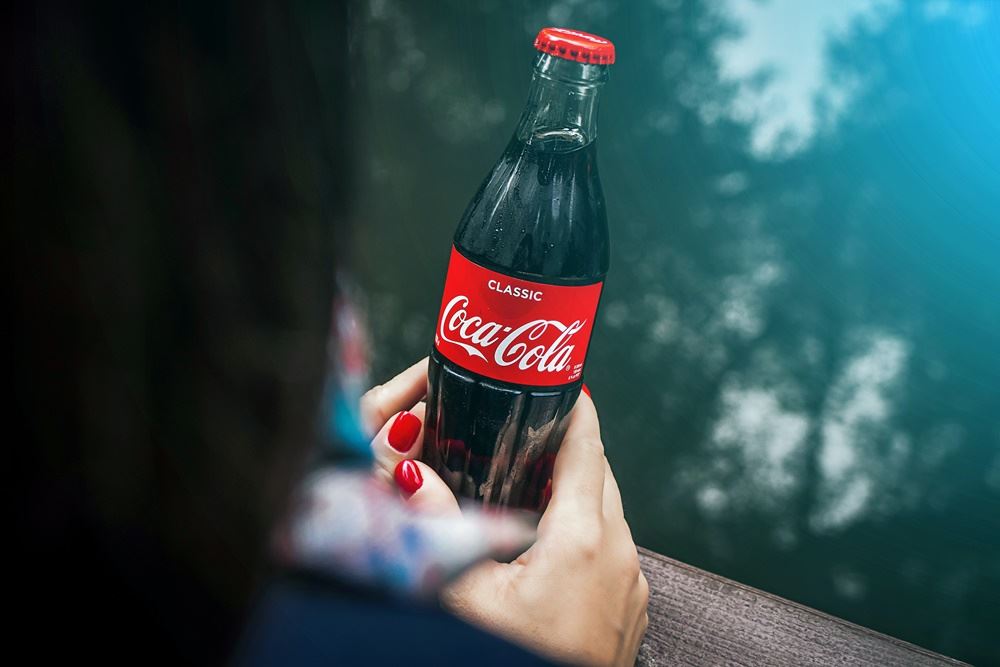 Person holder en coca cola flaske i hånden