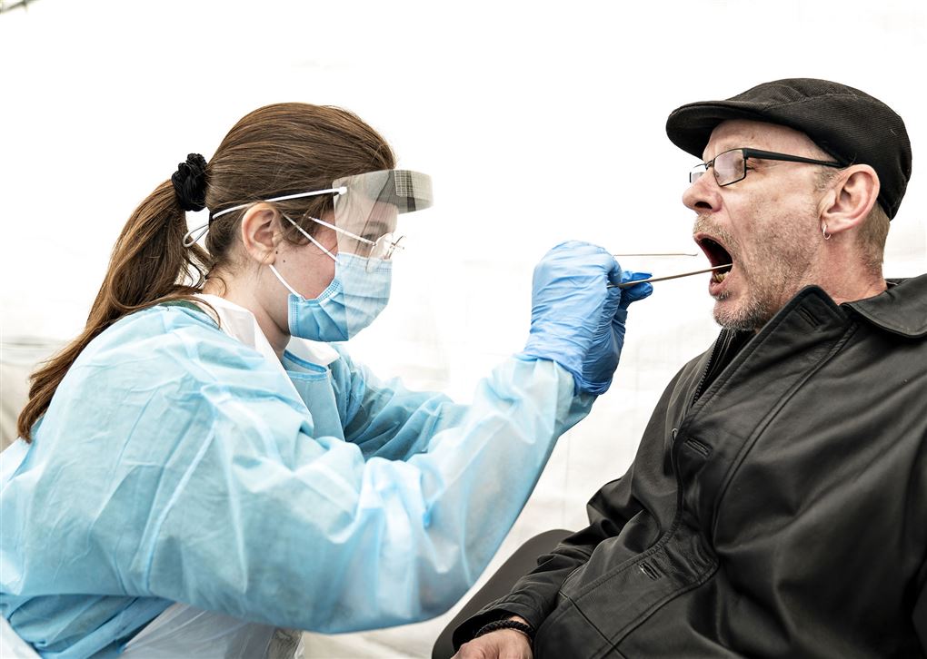 En sundhedsarbejder foretager en coronatest på mand med kasket