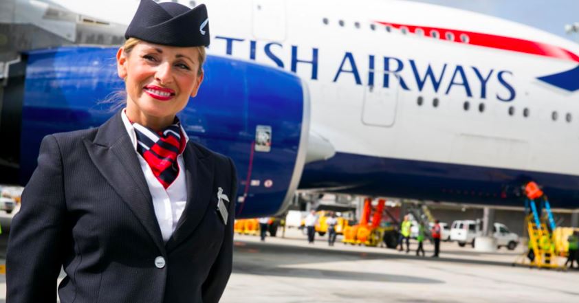 En smilende stewardesse foran et BA-fly