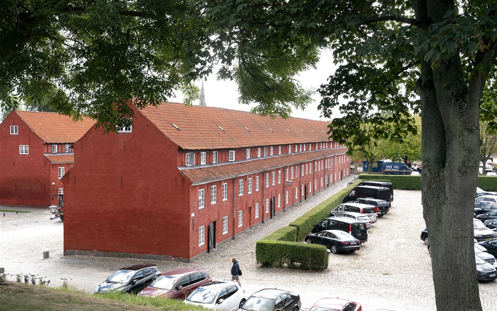 Forsvarets Efterretningstjeneste holder til på Kastellet i København som her er afbilledet. Det er nogle gamle rødmalede bygninger. Der ses også en parkeringsplads på billedet.