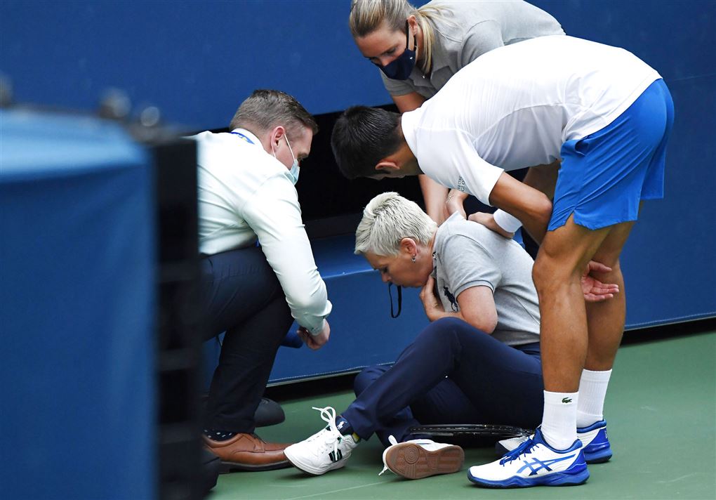 Tennisspilleren Novak Djokovic står ved en linjedommer som han har ramt på halsen