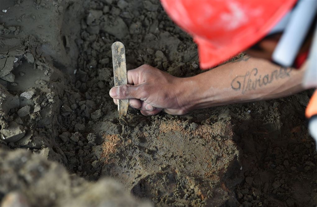 nærbillede af en arkæolog der arbejder i udgravningen