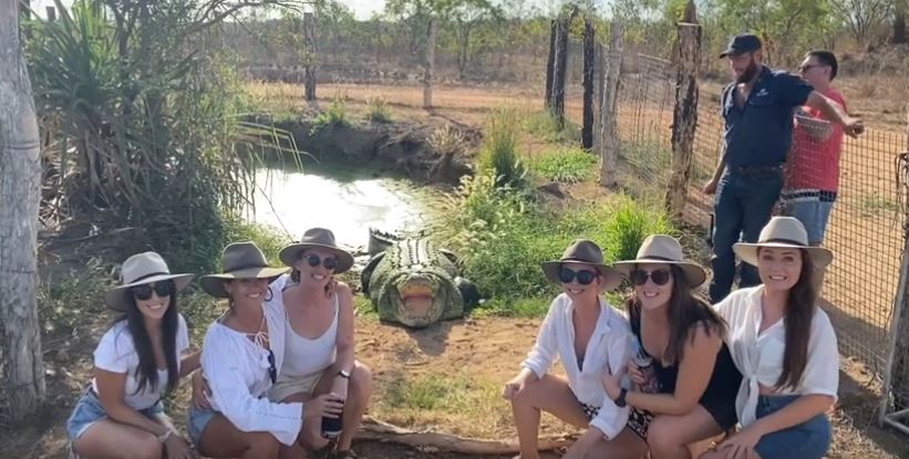 Seks unge kvinder i hatte med en kæmpe krokodille bag dem