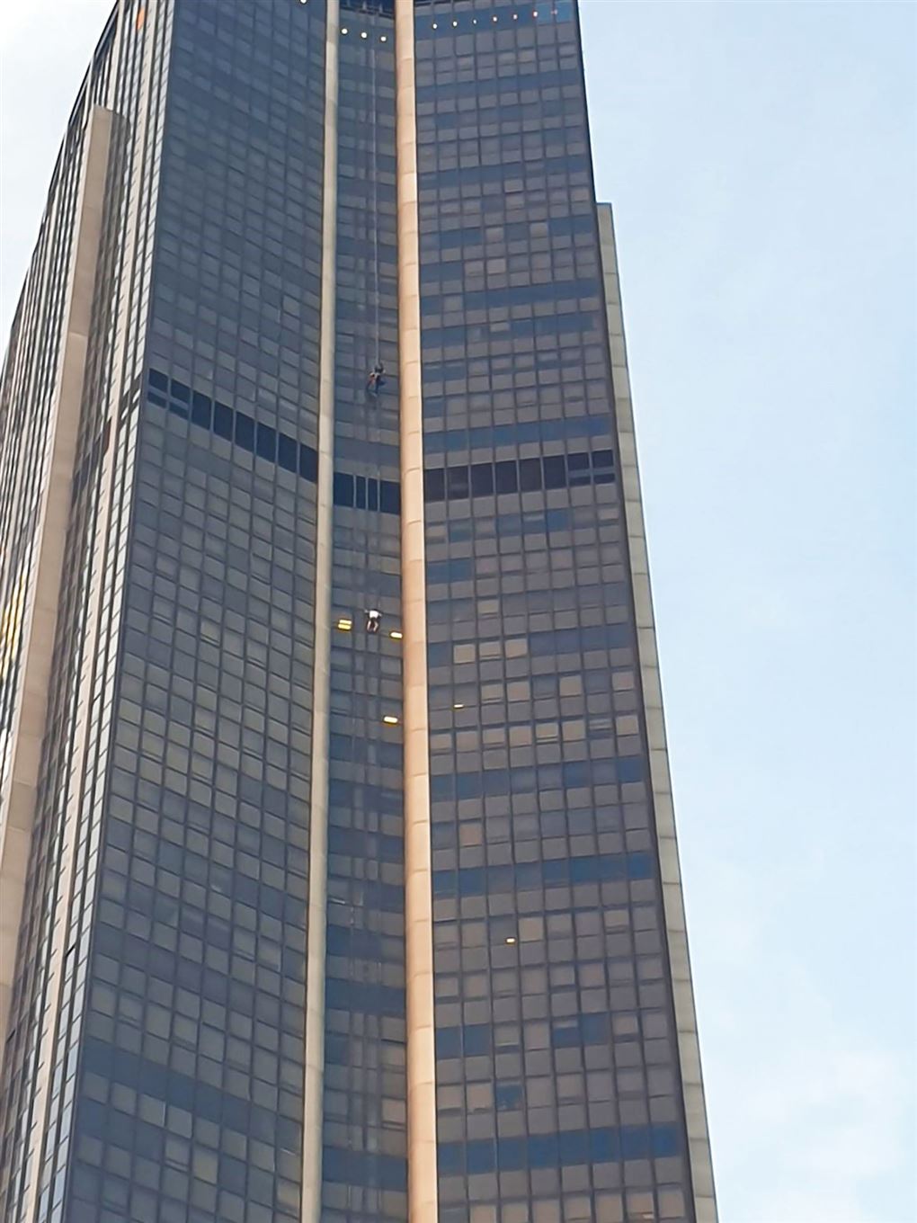 En lille prik viser en mand på vej op ad facaden på en skyskraber