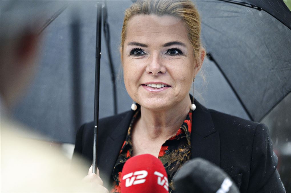 Venstres Inger Støjberg smiler mens hun står under paraply