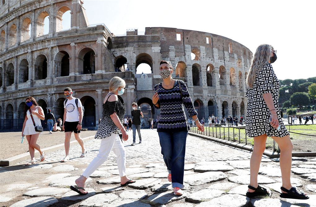 Turister med mundbind går foran Colosseum