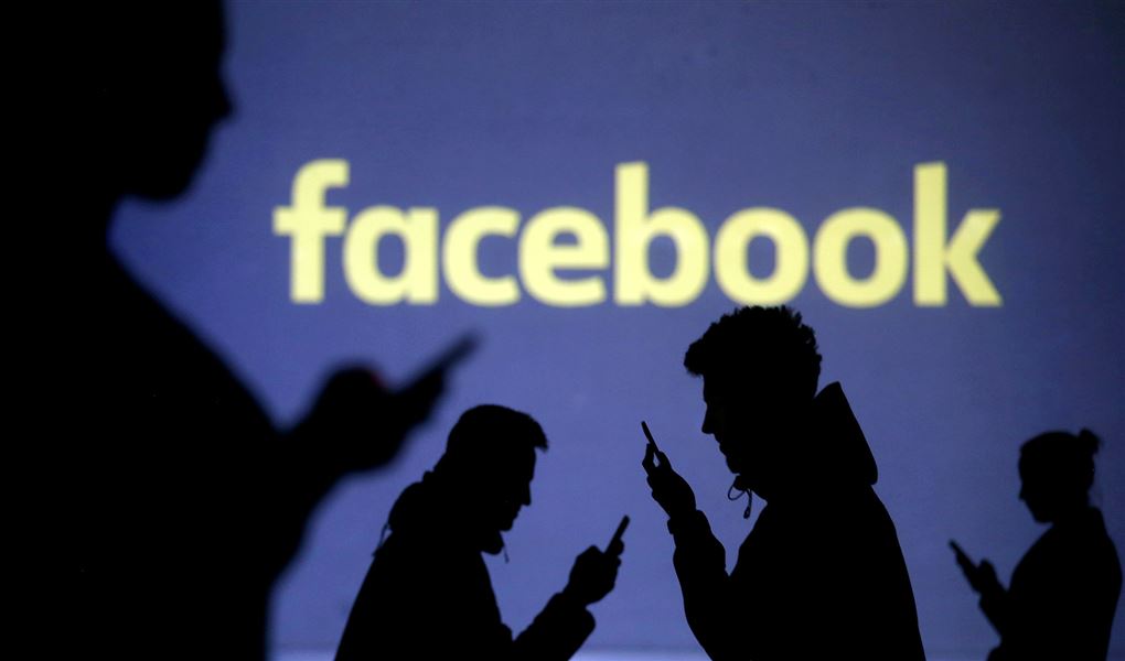 Silhoutter med mobiltelefoner og et Facebook skilt i baggrunden