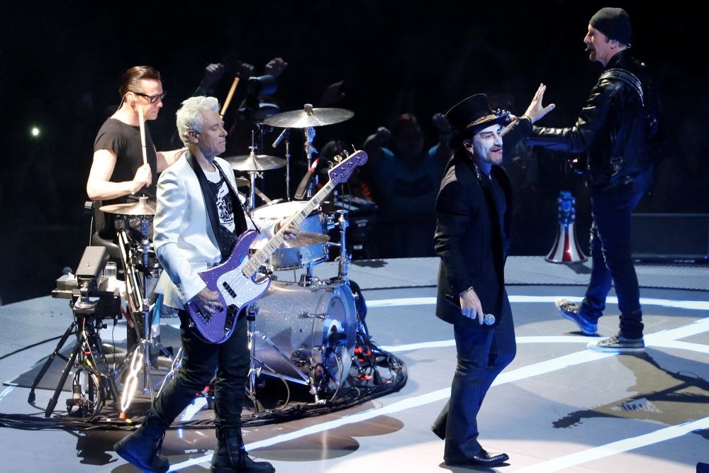 Medlemmer af bandet U2 står på scenen