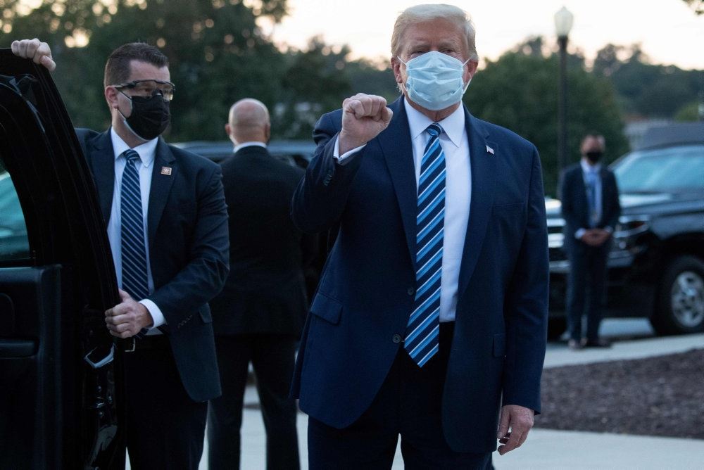 Donald Trump med ansigtsmaske omgivet af sikkerhedsfolk 