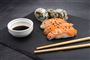 sushi, spisepinde og soyasauce anrettet på bræt 