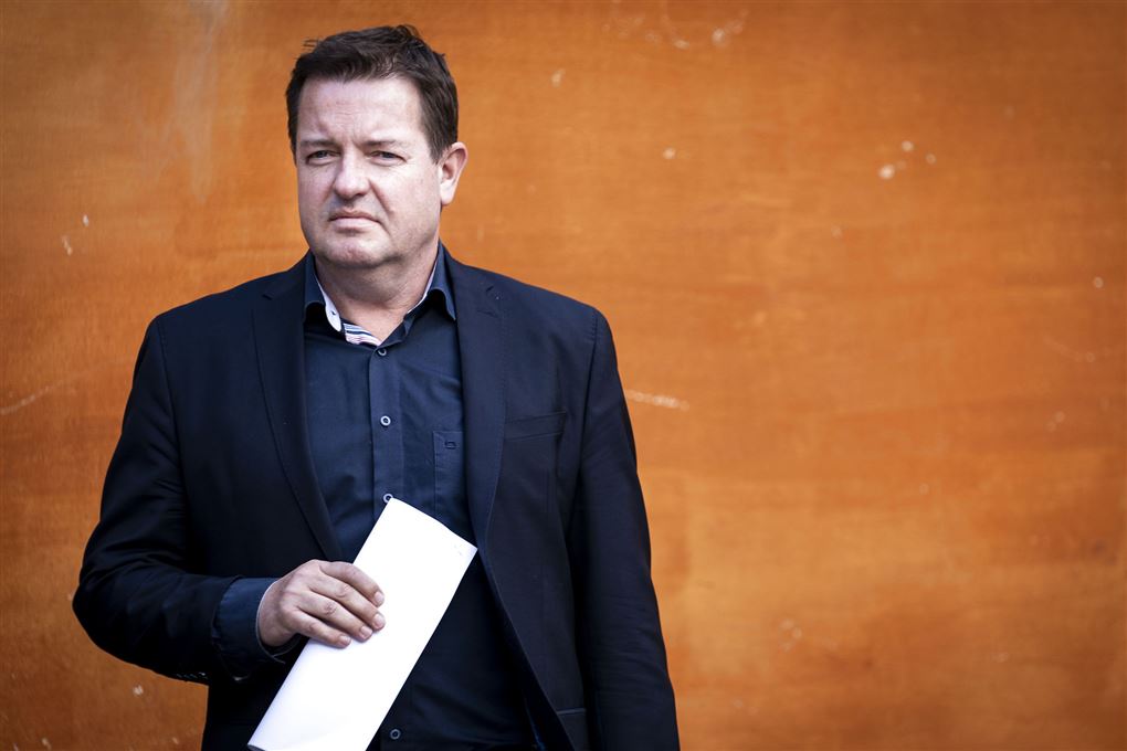 politikeren Jens Rohde står med papir i hånden op ad orange mur 
