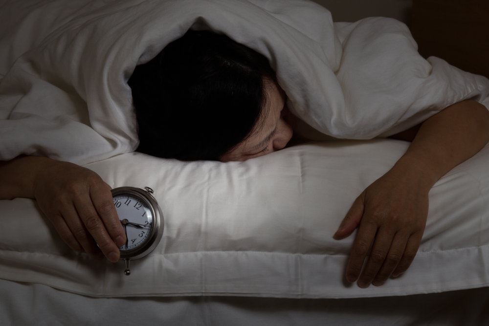 En mand sover med et vækkeur i hånden