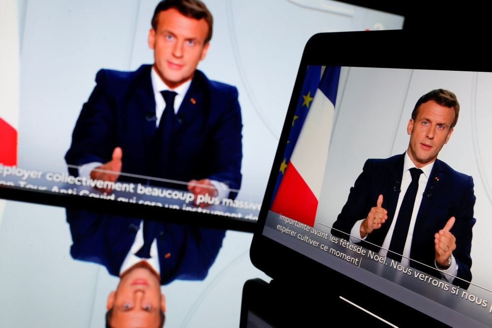 Præsident Macron holder tale til folket ved et skrivebord med det franske flag i baggrunden