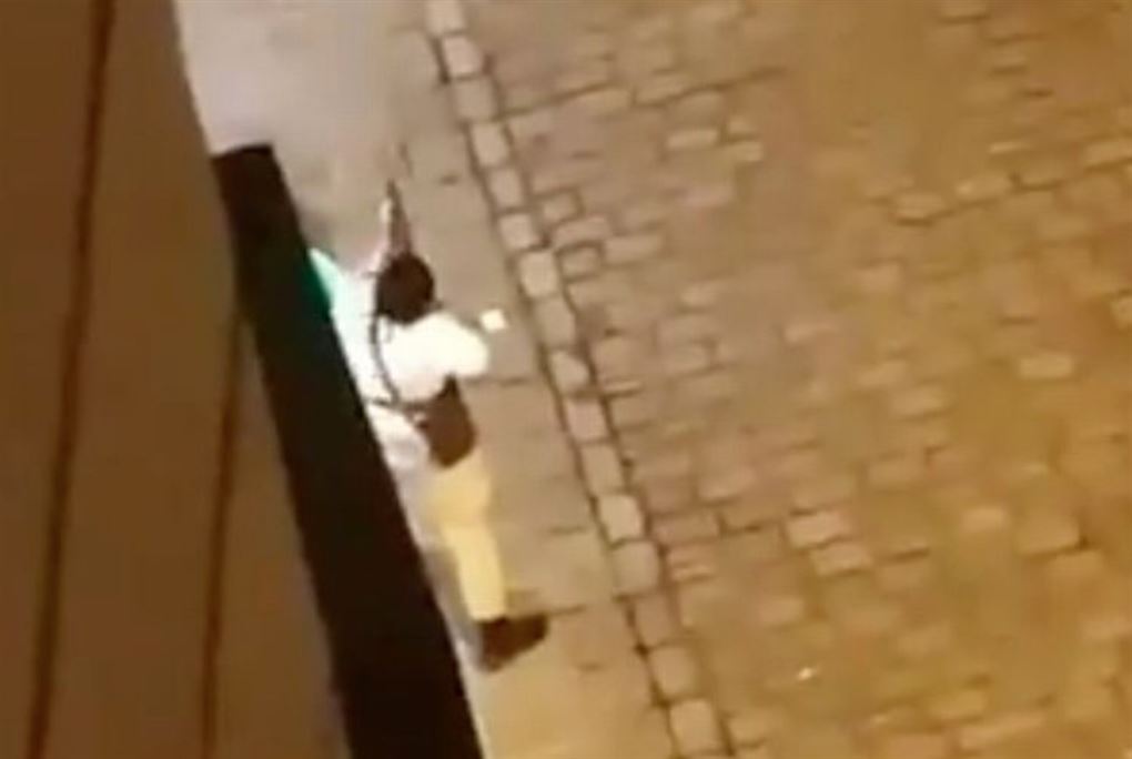 En mand klædt i hvidt skyder ned ad en gade