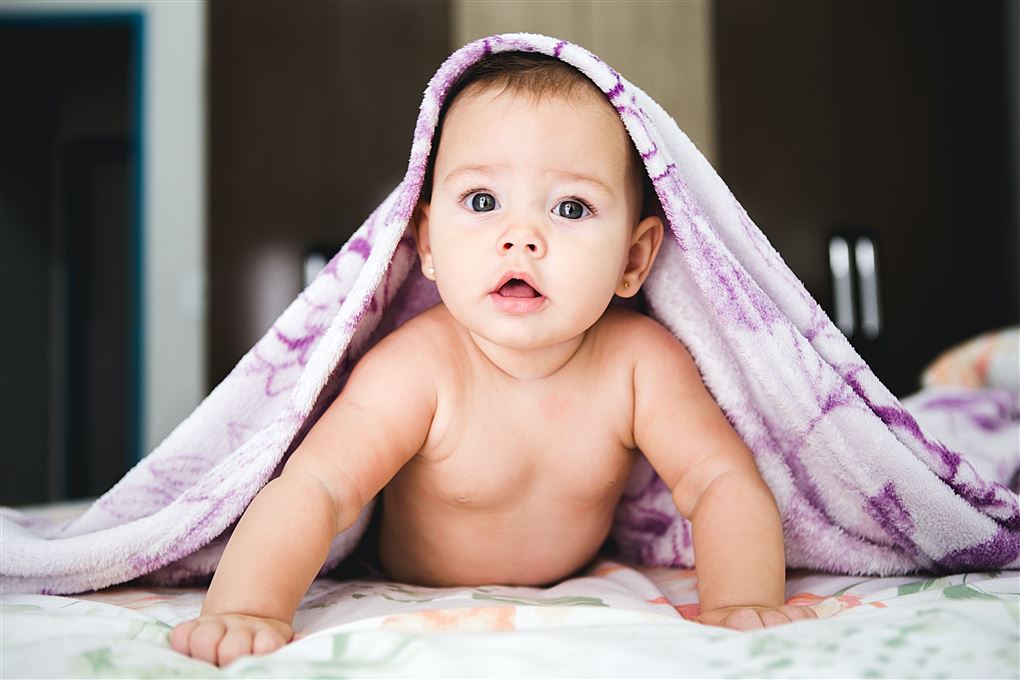 baby under håndklæde kigger