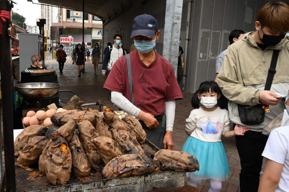 En kinesisk mand og en lille pige på et marked med mundbind på.