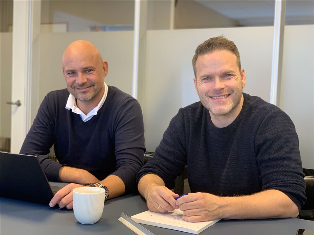 To smilende mænd ved et bord
