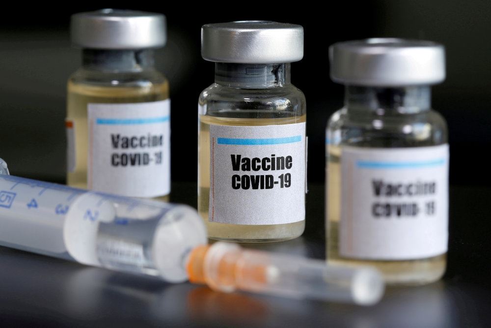 tre glas med vaccine står på bord 