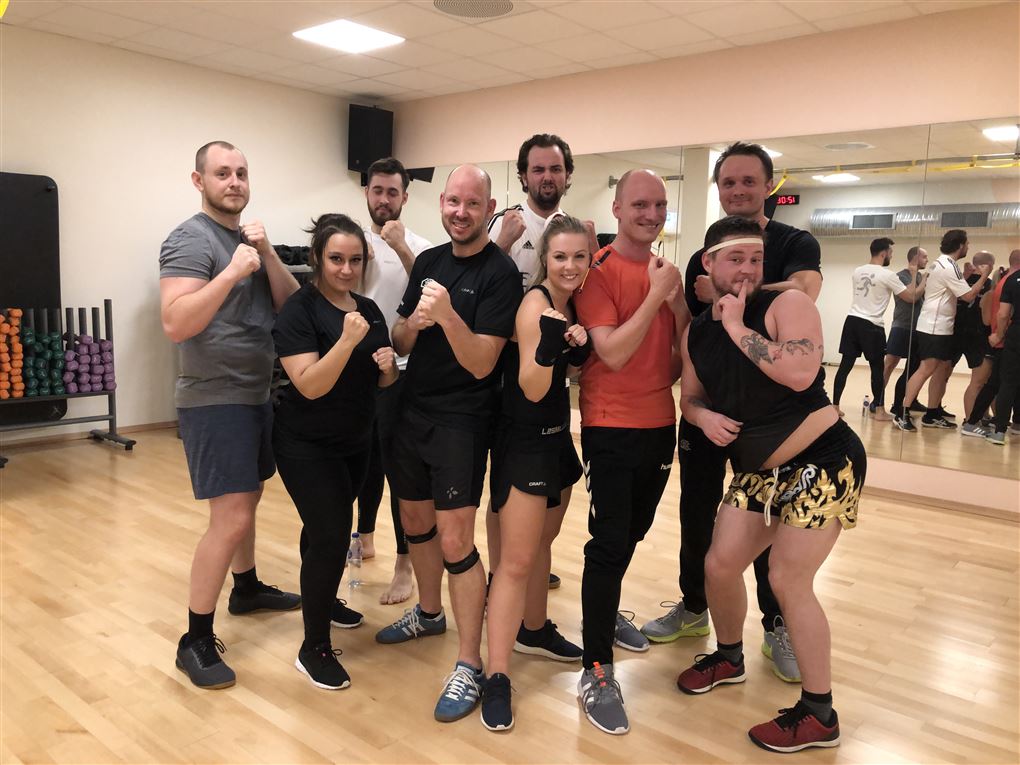 En flok almindelige mennesker i træningstøj i en gymnastiksal med spejl for enden