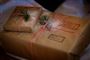 To julegaver der er pakket ind i brunt gavepapir. Den nederste har to stempler på.