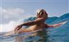 En nøgen kvinde på et surfbræt i bølgen blå